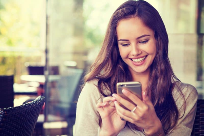 woman in cafe drinking coffee and using her mobile phone